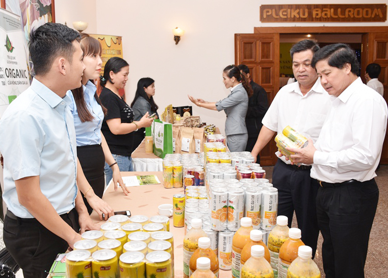 Thứ trưởng Bộ Nông nghiệp và PTNT Lê Quốc Doanh (bìa phải) và Phó Chủ tịch UBND tỉnh Kpă Thuyên xem sản phẩm chanh dây của Công ty DOVECO. Ảnh: Lê Nam